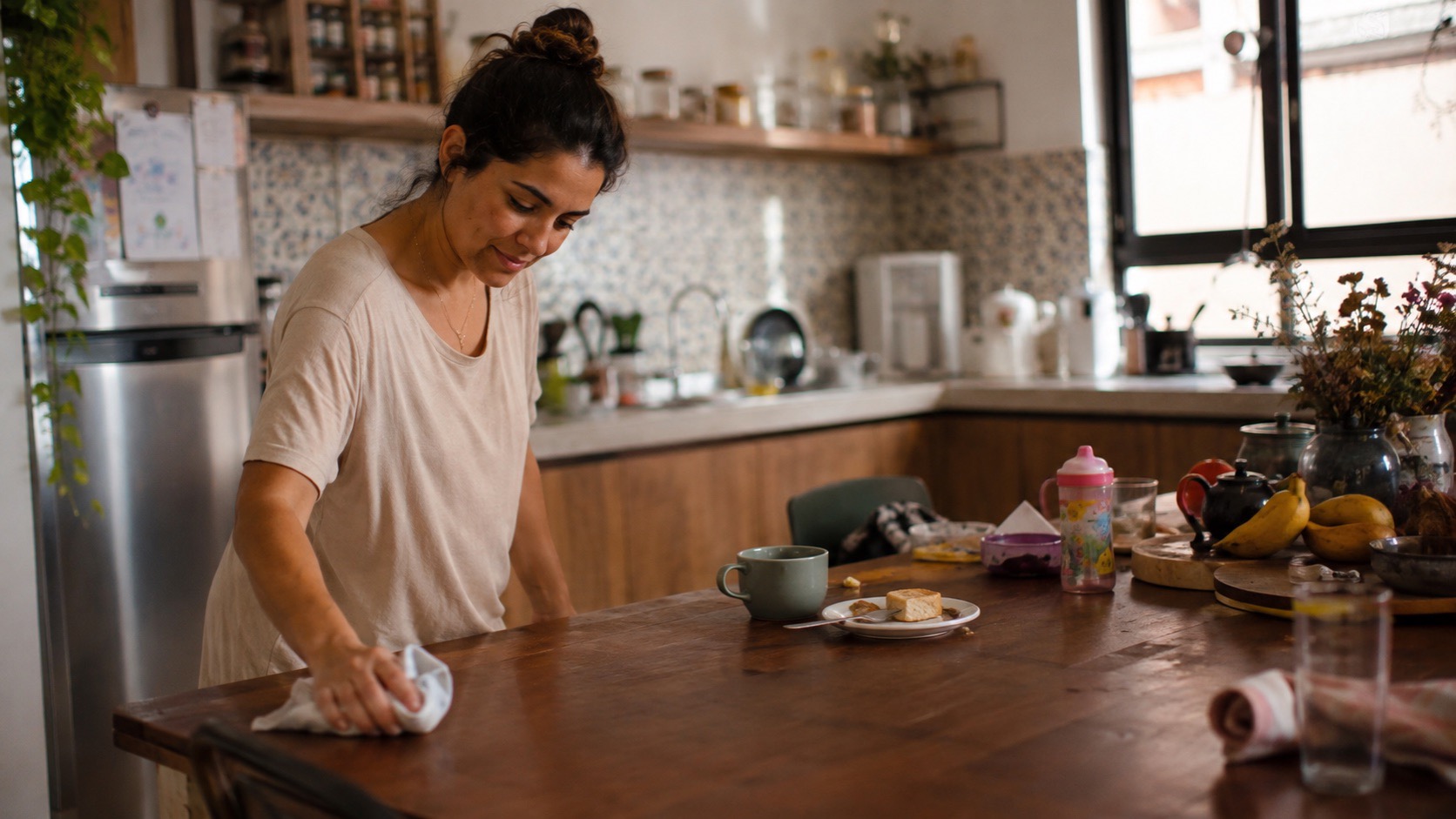 Mulher limpa apenas uma parte de uma mesa usada depois de uma semana movimentada