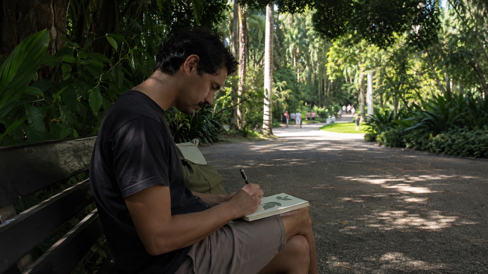 Homem desenha folhas em um caderno durante uma tarde sozinho no jardim botânico